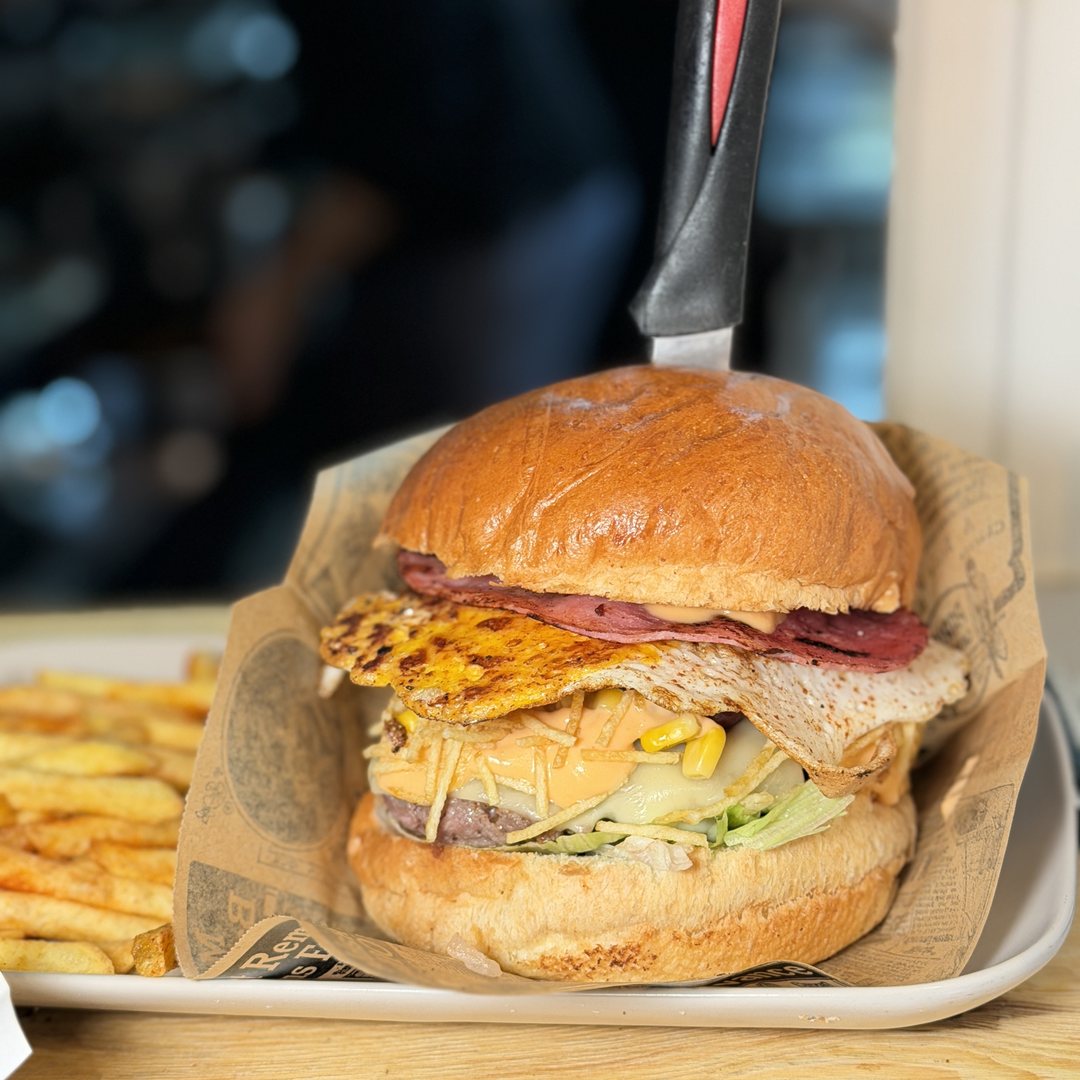 Photo du burger X-Tudo, steak, œuf, jambon, fromage, maïs et pommes paille, servi avec des frites chez Snack Brasil, le meilleur restaurant brésilien à Lyon 9, Vaise, près du métro Valmy