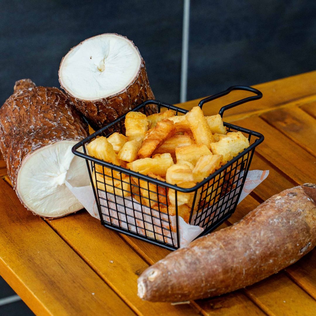 Photo de frites de manioc dans un panier en métal, à côté de racines de manioc coupées, chez Snack Brasil, le meilleur snack de Lyon 9 pour la cuisine brésilienne, quartier de Valmy, métro Valmy ligne D