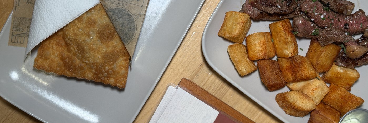 Photo vue du dessus d'une table en bois avec un pastel dans son papier journal et un plat de picanha et mandioca chez Snack Brasil, le meilleur restaurant pour un repas de groupe à Lyon 9, Vaise, Champvert